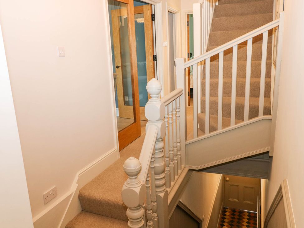 A staircase with beige carpet and white railing leading up and down with wooden doors in a hallway at The Loft in Ystradgynlais