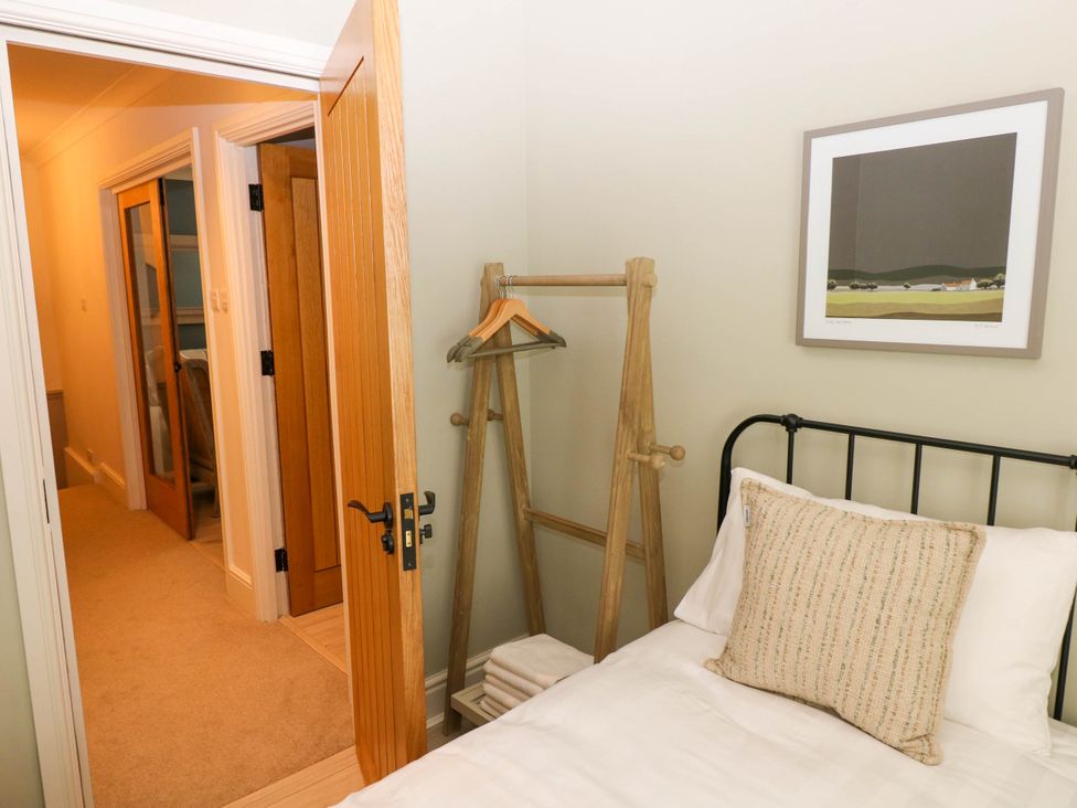A bedroom with a bed pillow clothes rack with hangers and folded towels in a corner and a framed picture on the wall at The Loft in Ystradgynlais