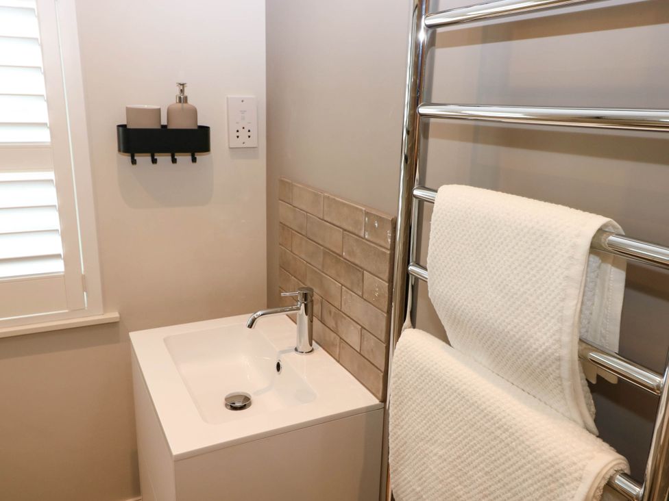 A bathroom sink with a faucet and a towel rack holding two white towels at The Loft in Ystradgynlais