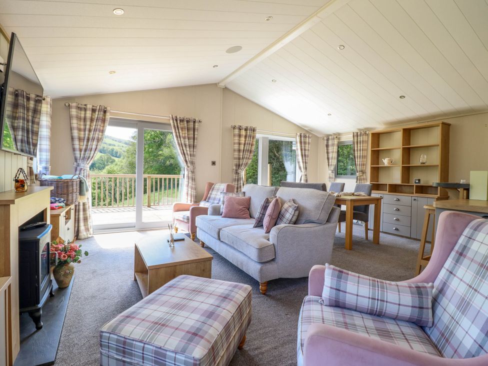 A living room with sofas armchairs coffee table and dining table with shelves at The Owlet in Dolwen near Llanidloes