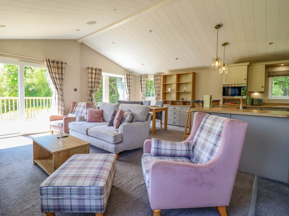 An open living room and kitchen area with armchairs a sofa coffee table and dining table at The Owlet in Dolwen near Llanidloes