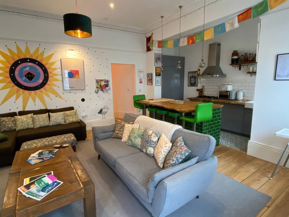 A living room with a sofa and a kitchen area at Church Retreat in St. Leonards-on-Sea