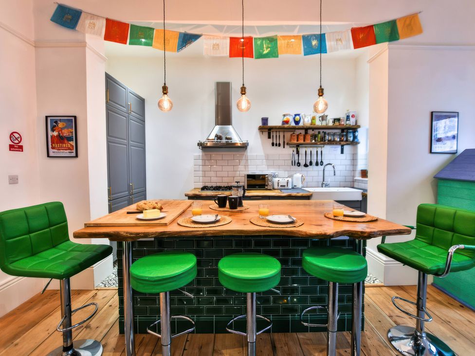 A kitchen with a bar island and green stools at Church Retreat in St. Leonards-on-Sea