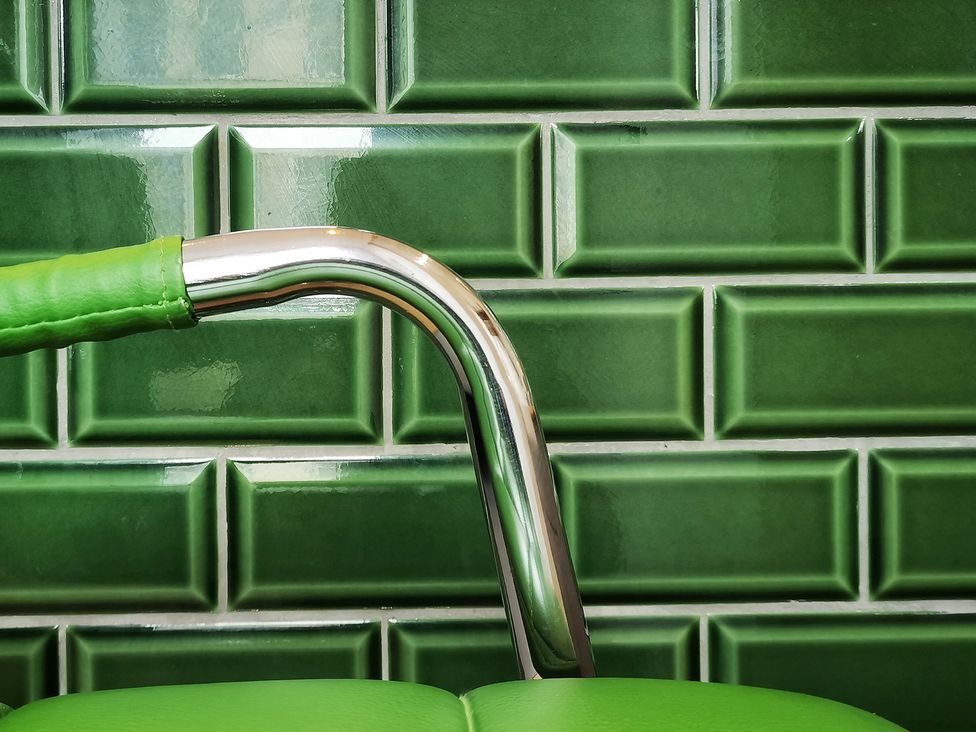 A chair armrest against green wall tiles at Church Retreat in St. Leonards-on-Sea