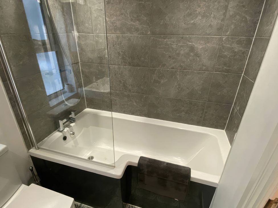 A bathroom with a bathtub and shower screen at Church Retreat in St. Leonards-on-Sea