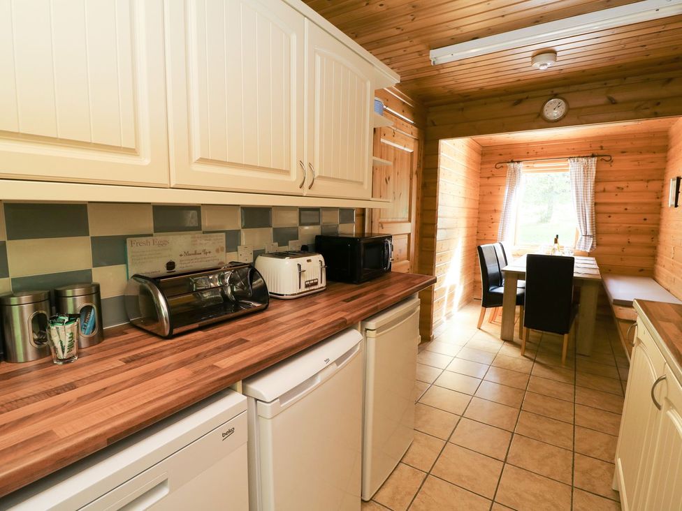 A kitchen with appliances and a dining area at Dan Y Coed in Beggar's Bush near Presteigne