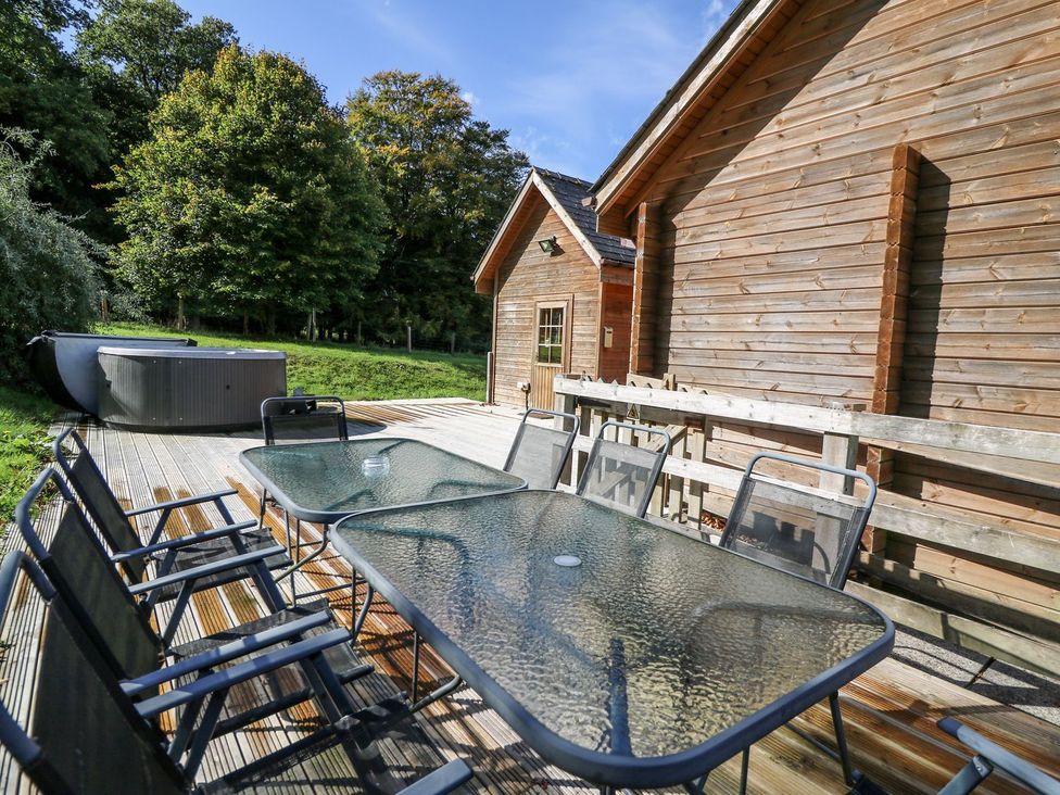 An outdoor area with a table, chairs, and hot tub at Dan Y Coed near Beggar's Bush