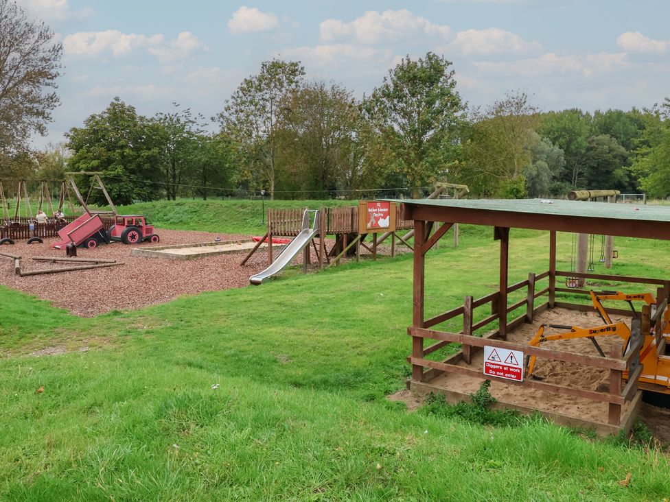 A playground with a slide, swings, and a sandbox at Molly (Cow Shed 6) Woodbridge