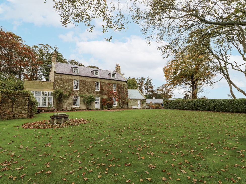 A house with a garden and trees at Elford Farmhouse Seahouses