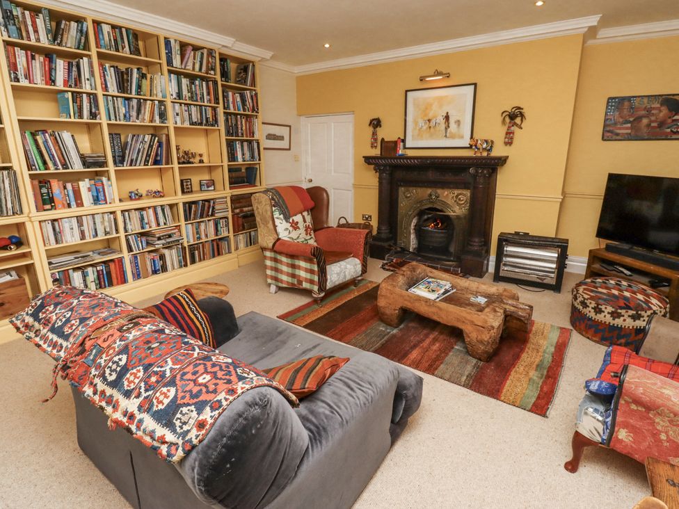 A living room with a fireplace and bookshelf at Elford Farmhouse in Seahouses