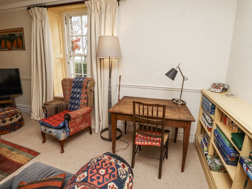 A living room with a desk and lamp at Elford Farmhouse in Seahouses
