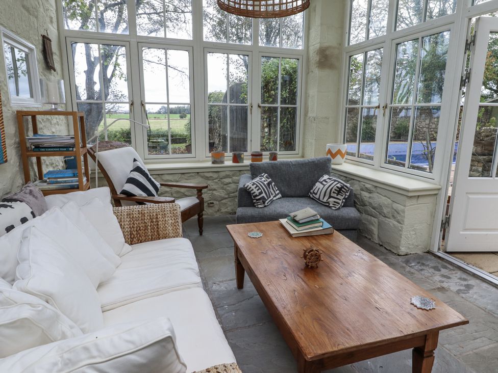 A conservatory with seating and a coffee table at Elford Farmhouse in Seahouses