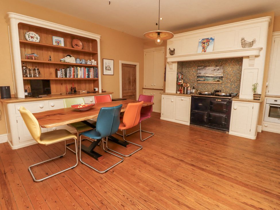 A kitchen with a wooden table and colorful chairs at Elford Farmhouse in Seahouses