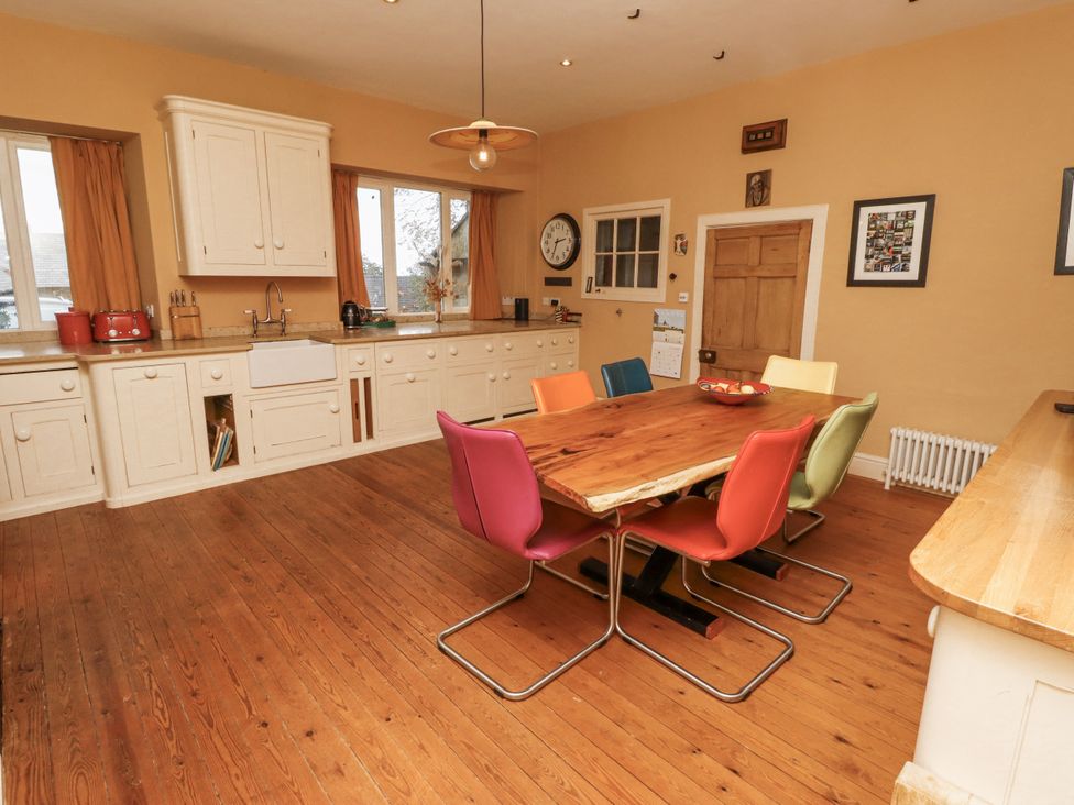 A kitchen with a dining table and colorful chairs at Elford Farmhouse in Seahouses