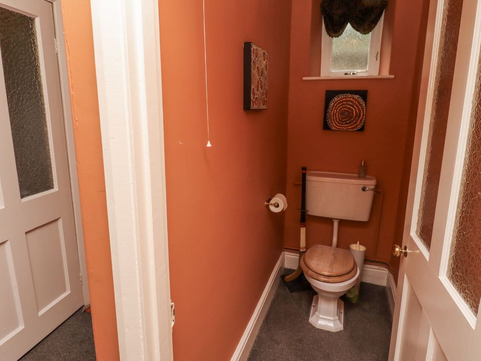 A bathroom with a toilet and wall art at Elford Farmhouse in Seahouses