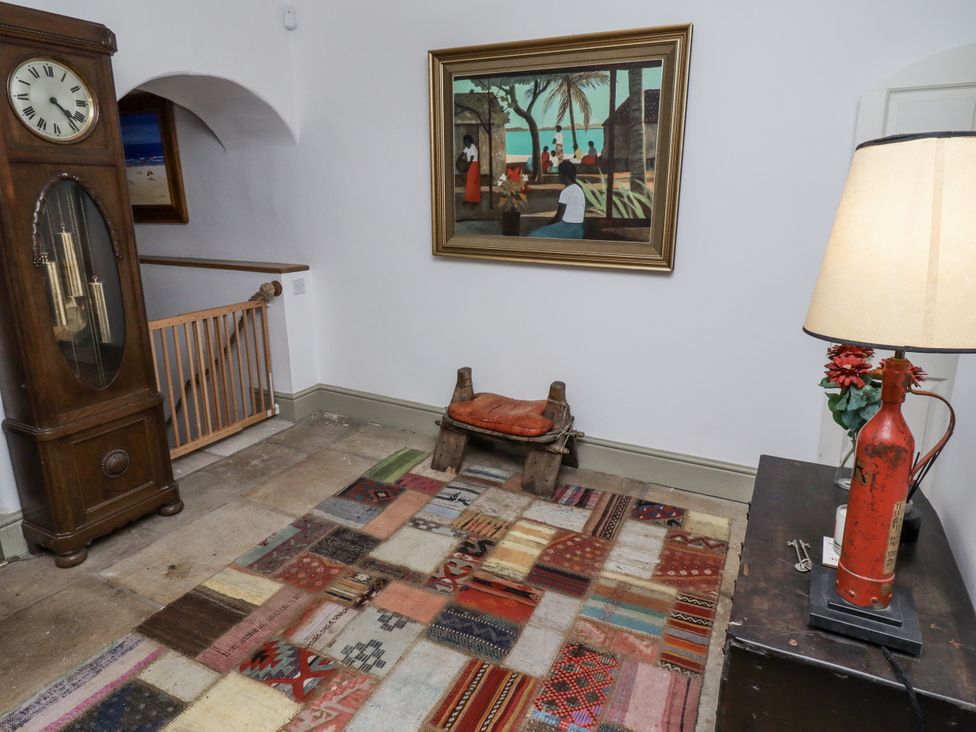 A hallway with a clock and rug at Elford Farmhouse in Seahouses
