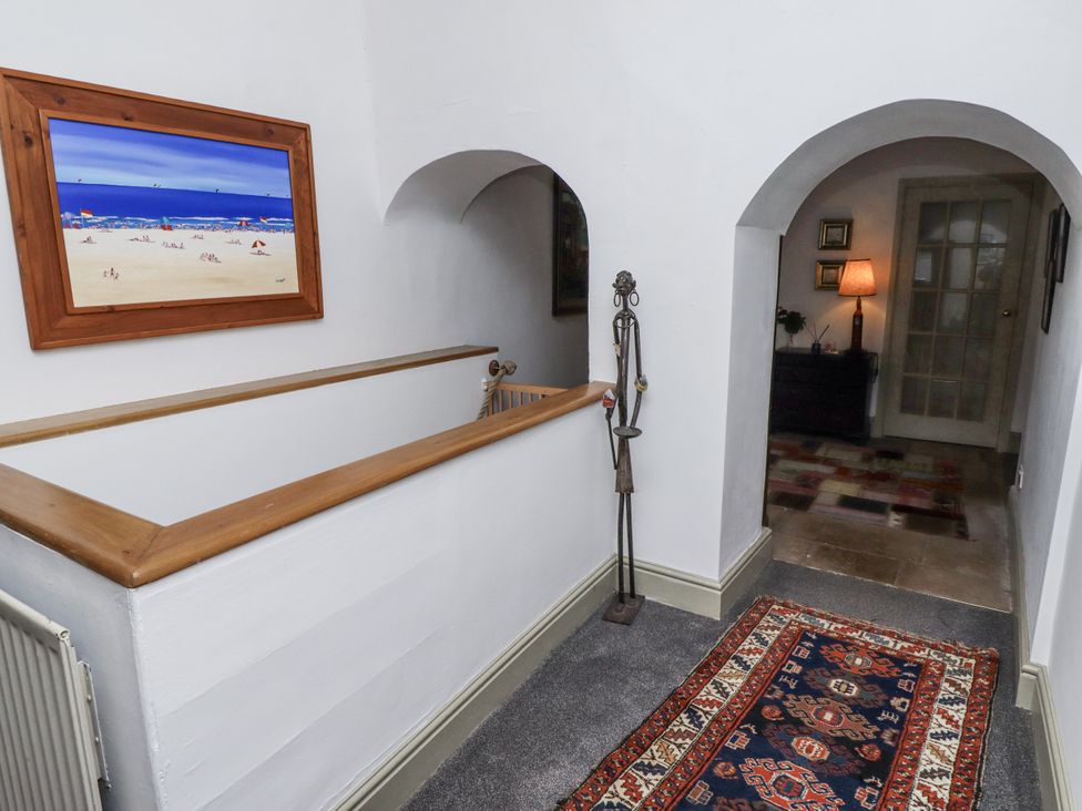 A hallway with a painting and a lamp at Elford Farmhouse in Seahouses