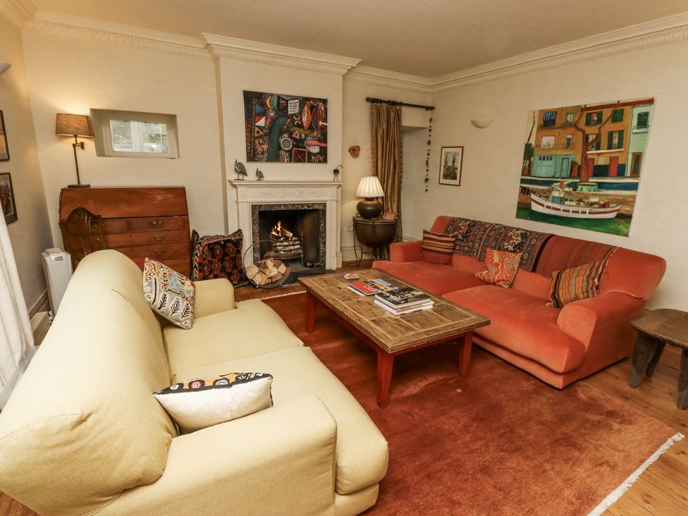 A living room with a sofa, armchair, and fireplace at Elford Farmhouse in Seahouses