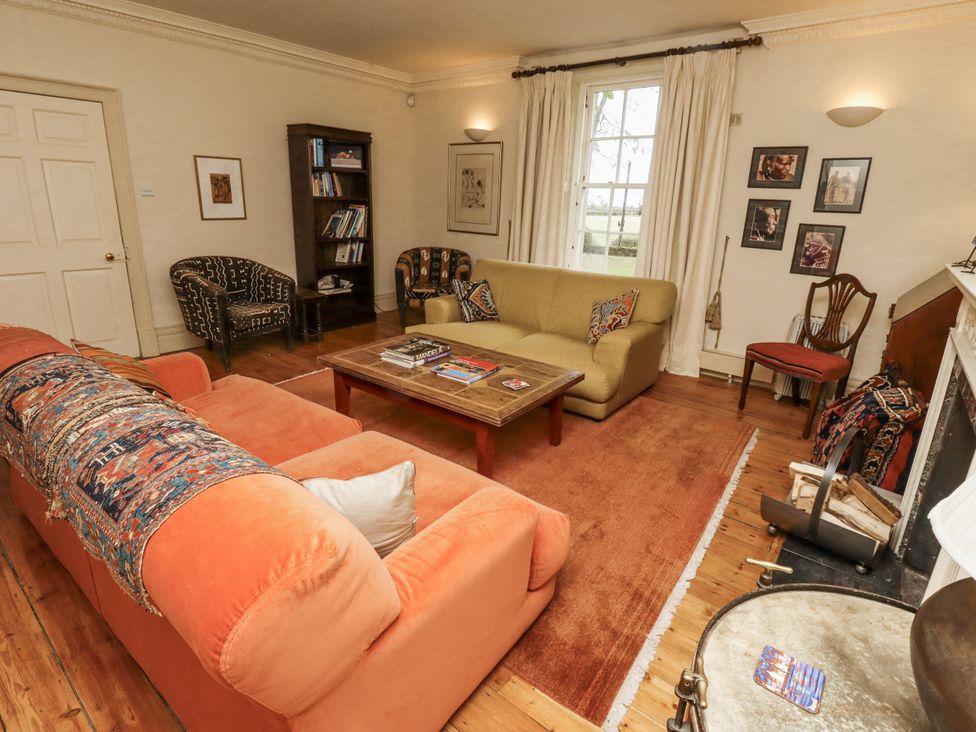 A living room with a sofa, armchair, and fireplace at Elford Farmhouse in Seahouses
