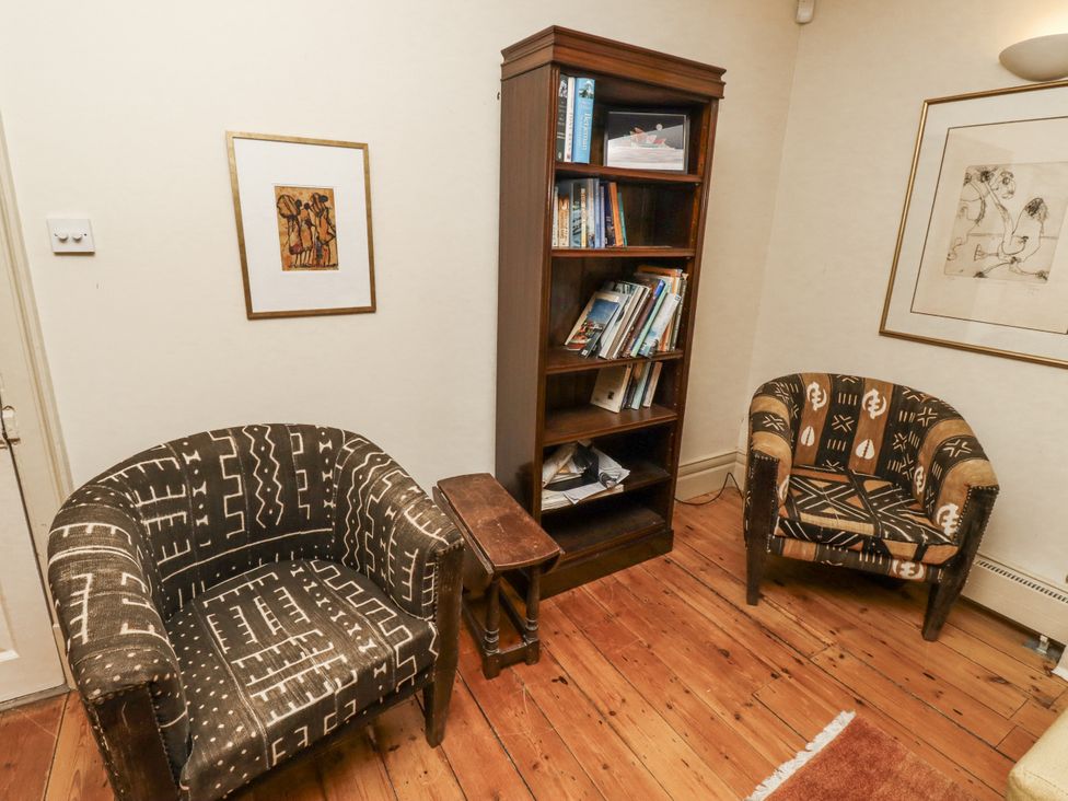 A sitting room with two armchairs and a bookshelf at Elford Farmhouse Seahouses