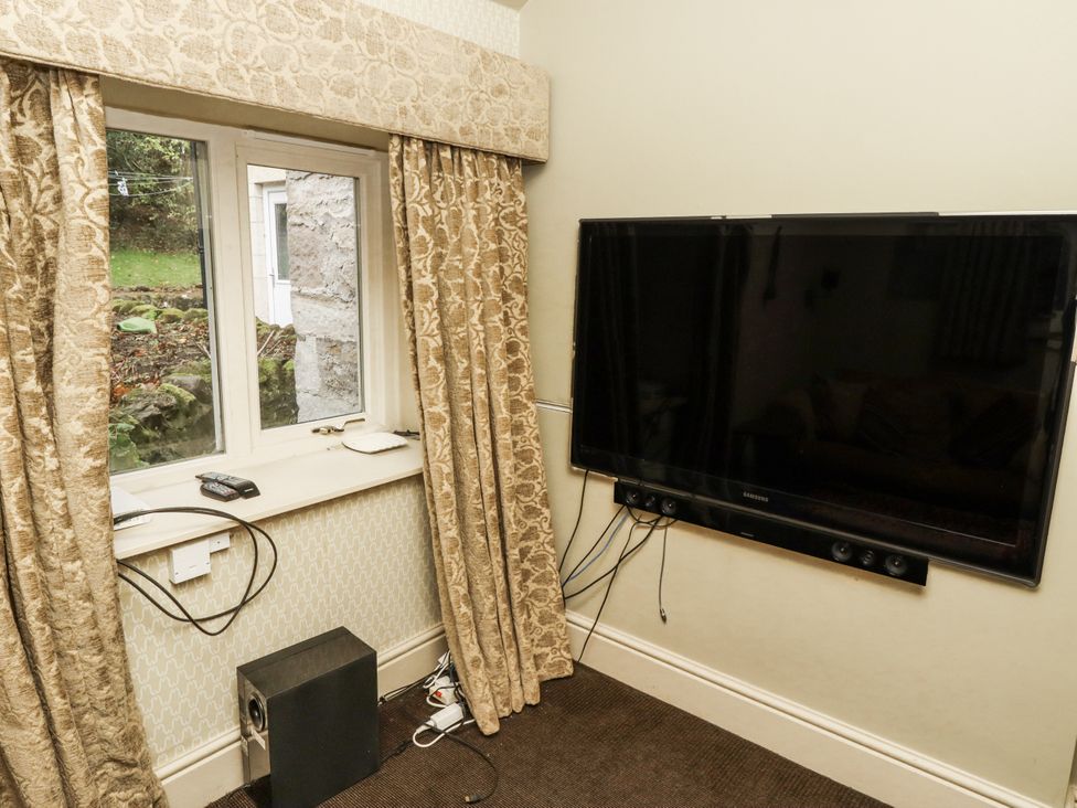 A living room with a television and window at Elford Farmhouse Seahouses
