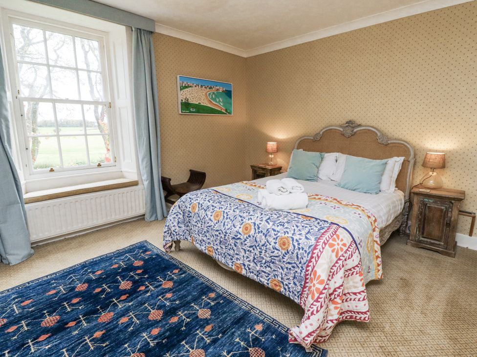A bedroom with a bed and paintings at Elford Farmhouse in Seahouses