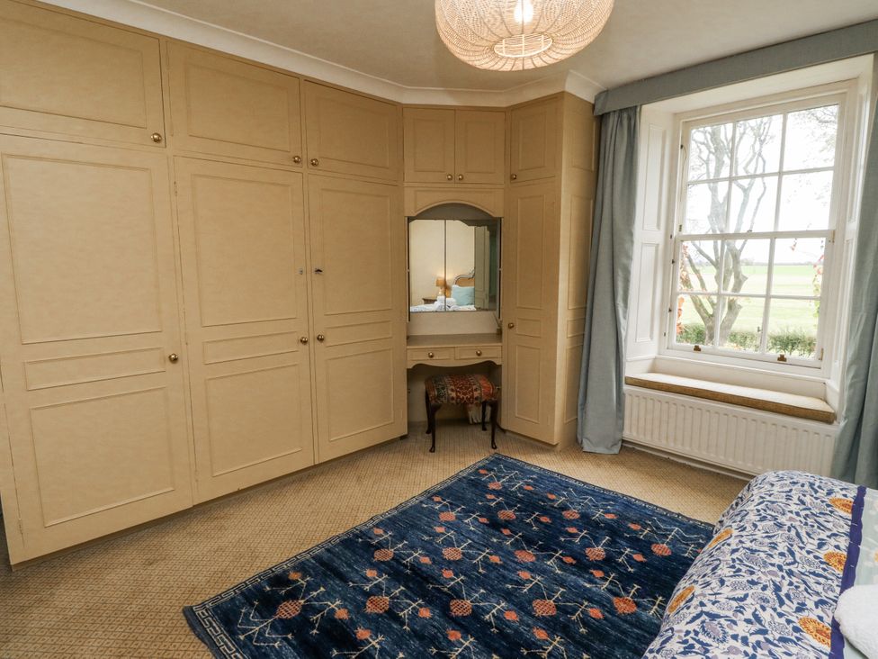 A bedroom with a wardrobe and a vanity at Elford Farmhouse Seahouses