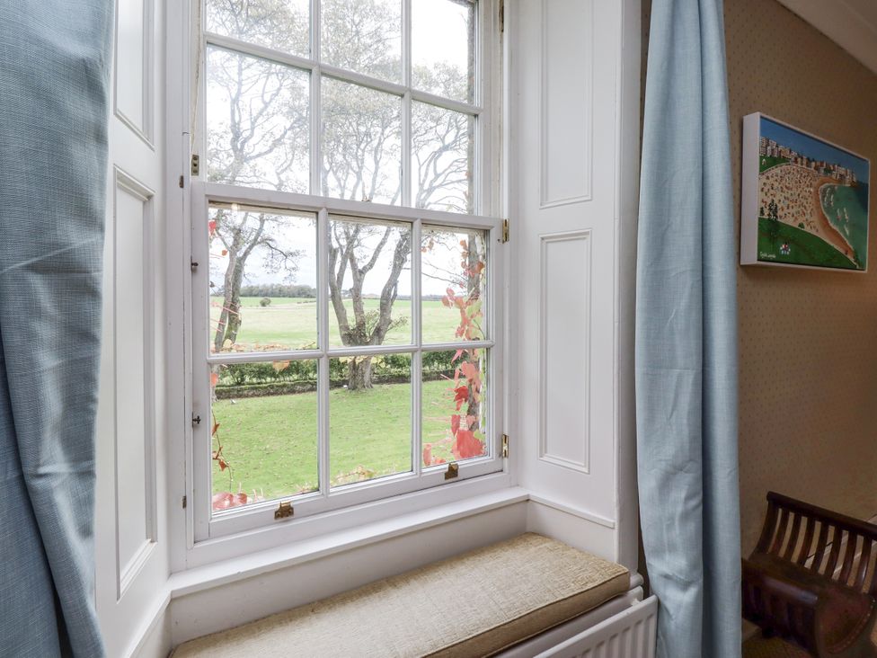 A window with a view of grass and trees at Elford Farmhouse in Seahouses