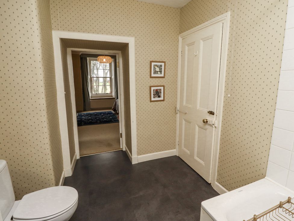 A bathroom with a toilet and door at Elford Farmhouse in Seahouses