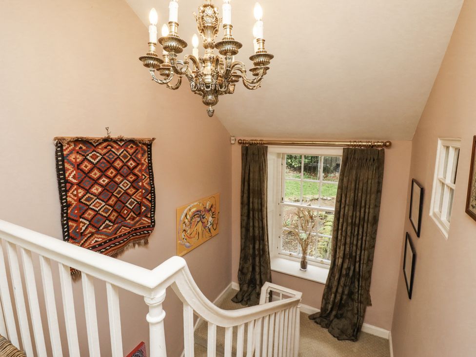 A staircase with a chandelier and wall art at Elford Farmhouse in Seahouses