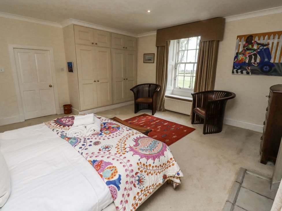 A bedroom with a bed and wardrobe at Elford Farmhouse in Seahouses