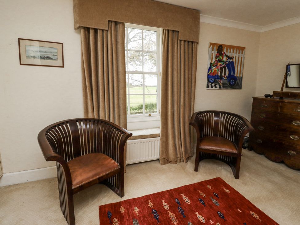 A sitting room with two chairs and a window at Elford Farmhouse Seahouses