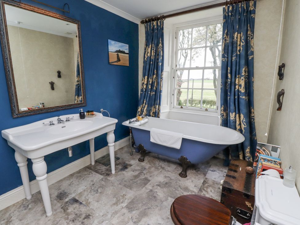A bathroom with a bathtub and sink at Elford Farmhouse in Seahouses
