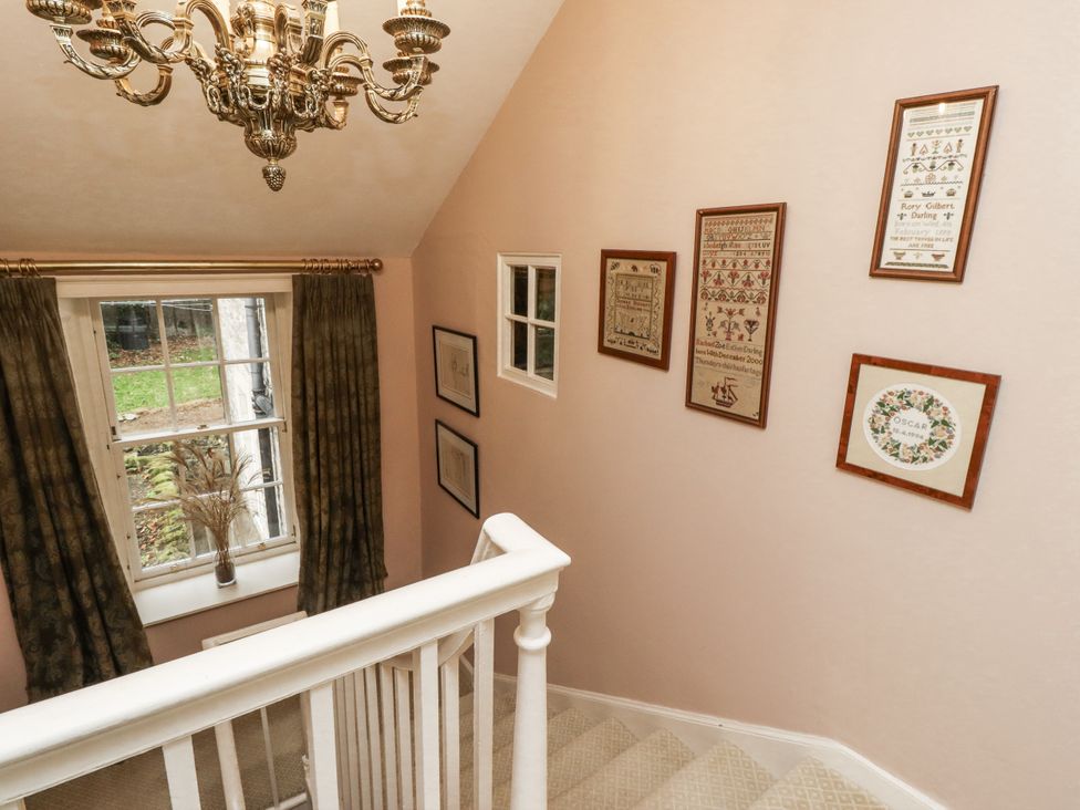 A staircase with chandelier and framed artwork at Elford Farmhouse in Seahouses
