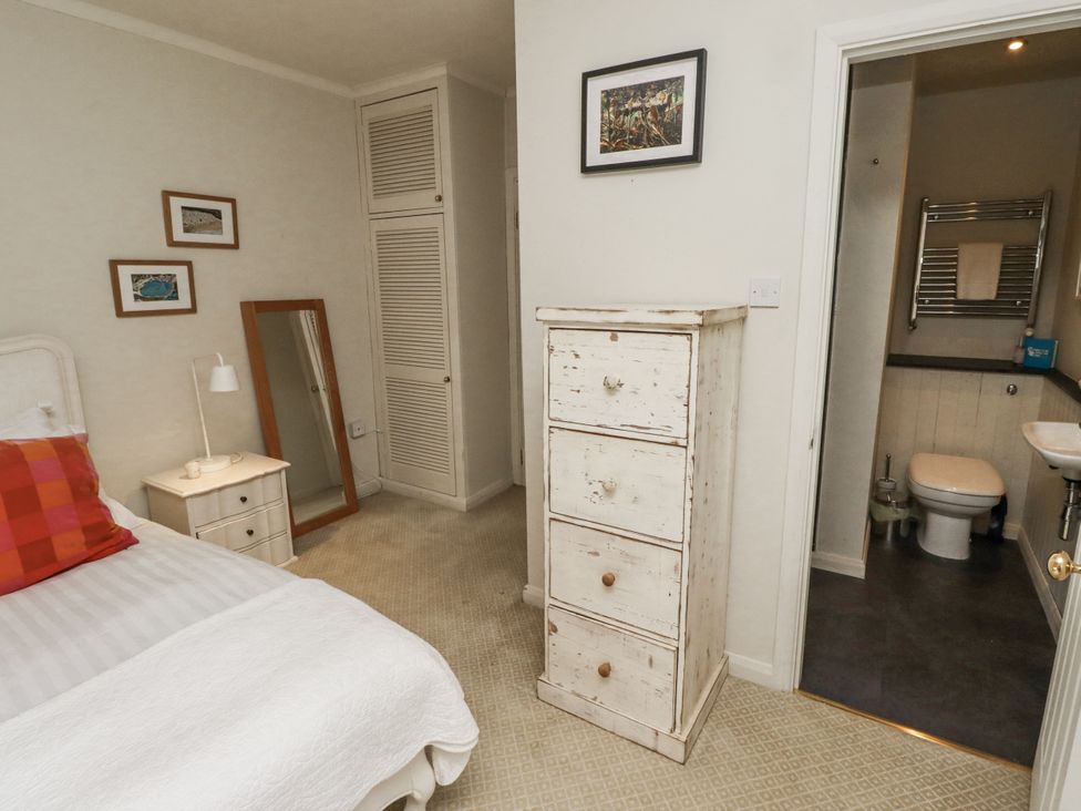 A bedroom with a bed, mirror, and chest of drawers at Elford Farmhouse Seahouses