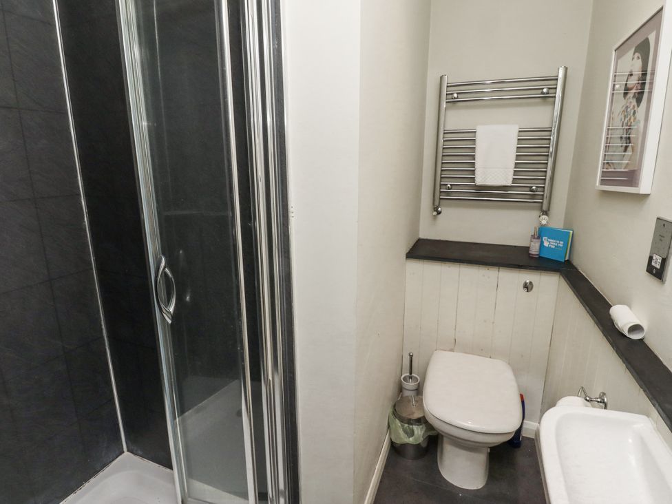 A bathroom with a shower, toilet, towel rail, and sink at Elford Farmhouse in Seahouses