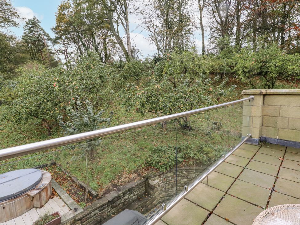 An outdoor area with a hot tub and balcony overlooking a garden at Elford Farmhouse in Seahouses