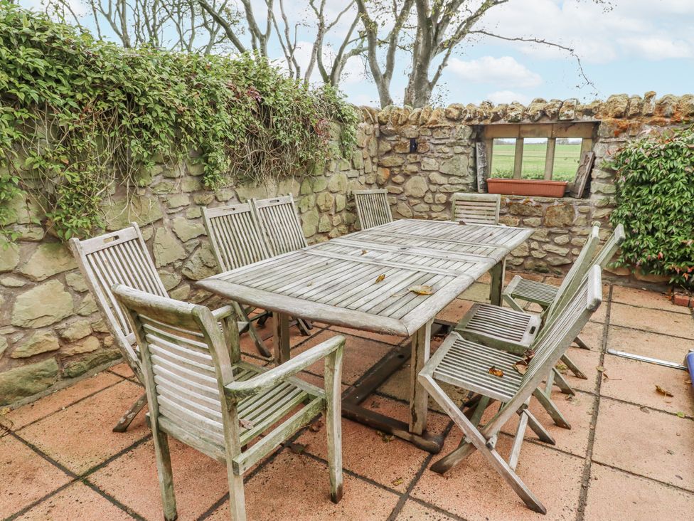 A garden with a wooden table and chairs at Elford Farmhouse in Seahouses