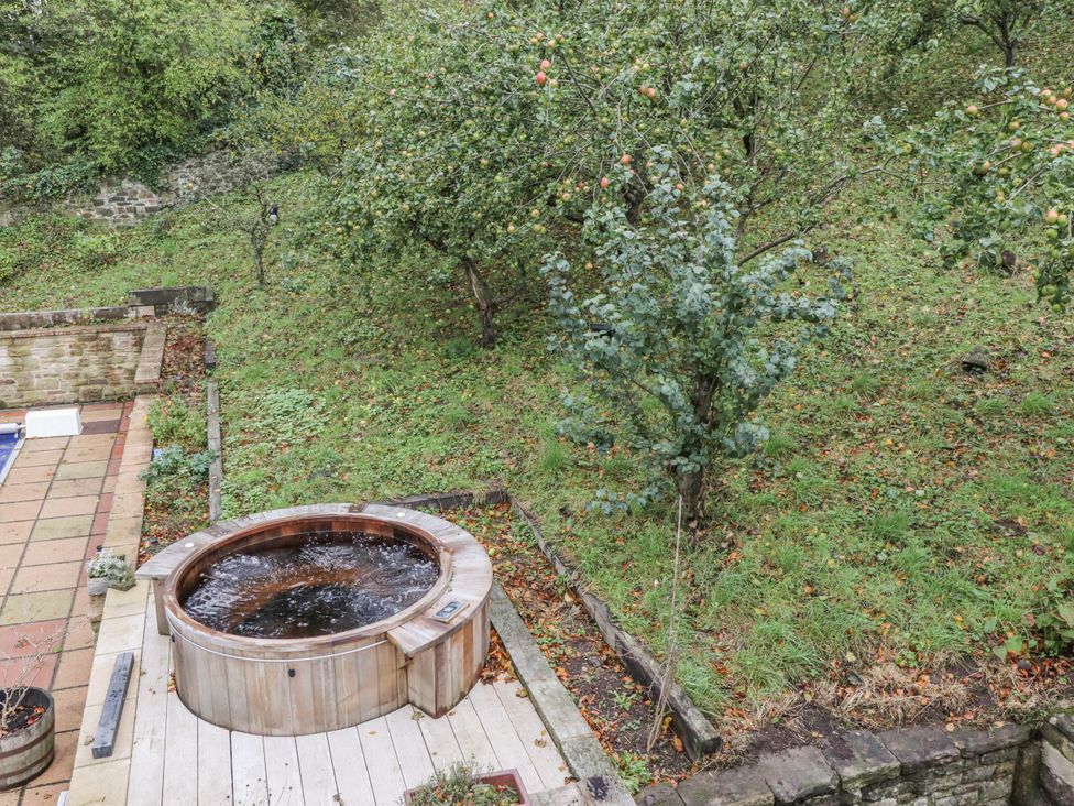 A garden with a hot tub and trees at Elford Farmhouse in Seahouses