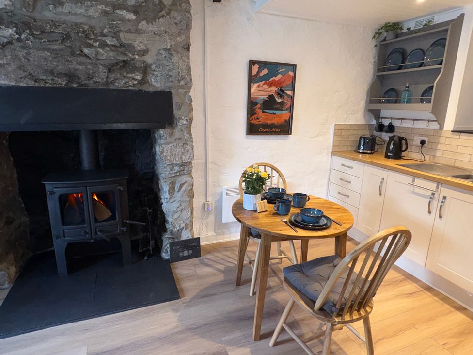 A kitchen with a table and chairs near a wood stove at 4 Old Tanrhiw Beddgelert
