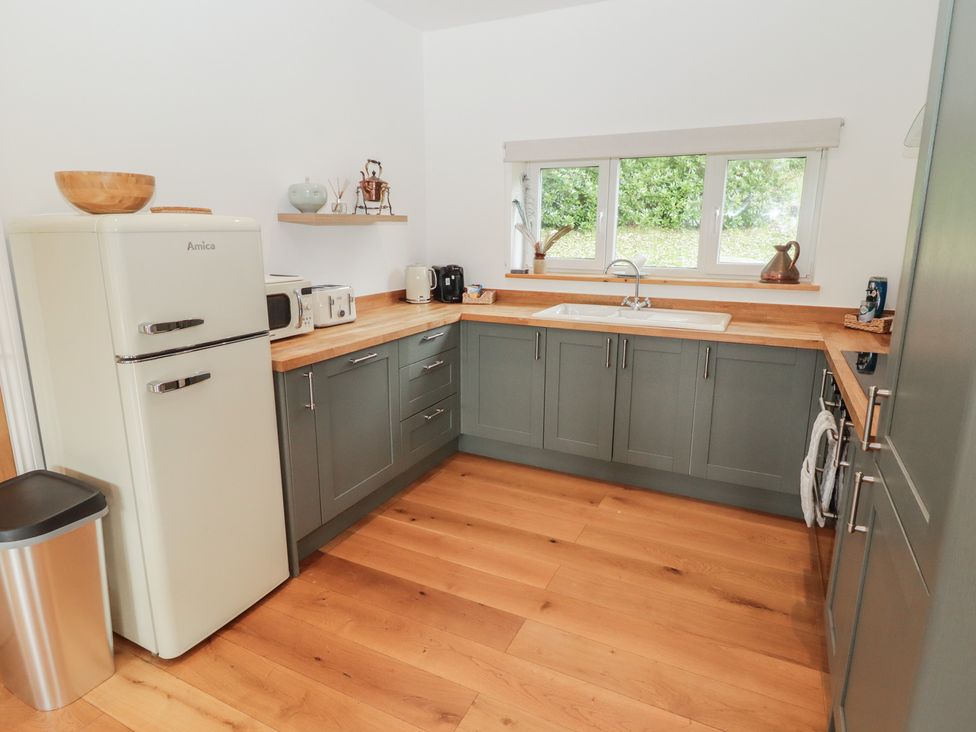 A kitchen with a fridge, microwave, sink and cabinets at The Lodge in Bridgend