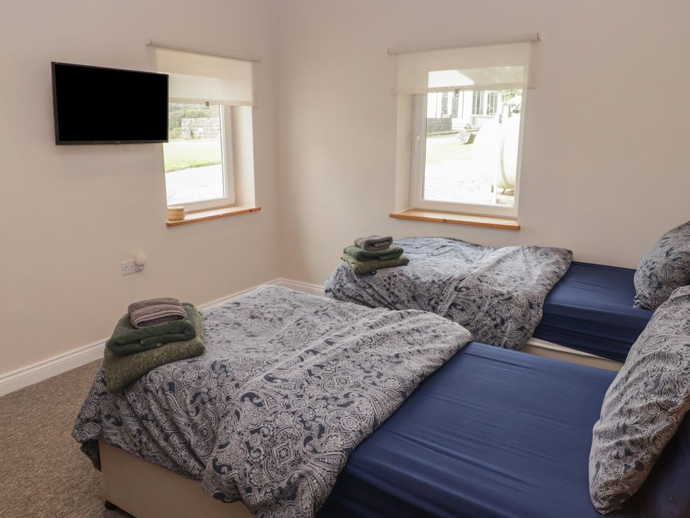 A bedroom with two beds and a television at The Lodge in Bridgend