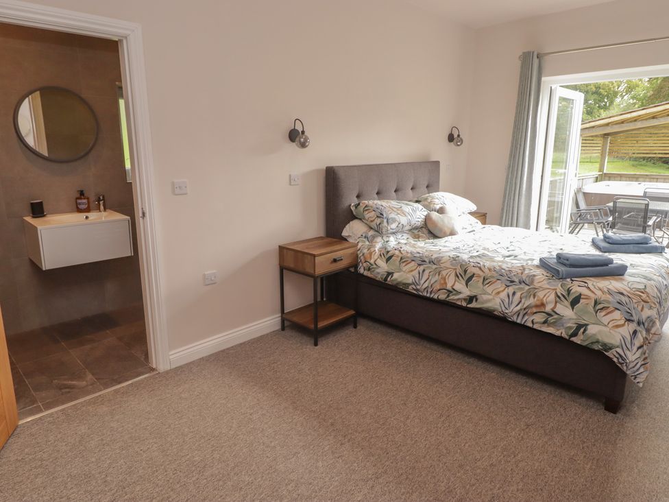 A bedroom with a bed and bathroom sink at The Lodge in Bridgend
