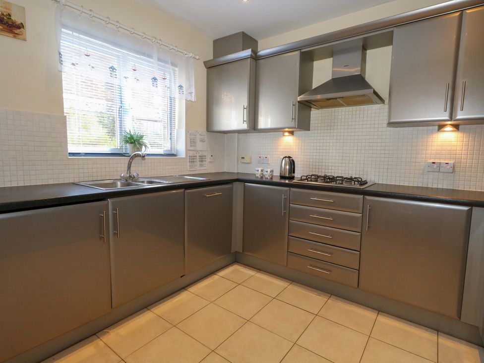 A kitchen with grey cabinets and a sink at Farthings in Weymouth