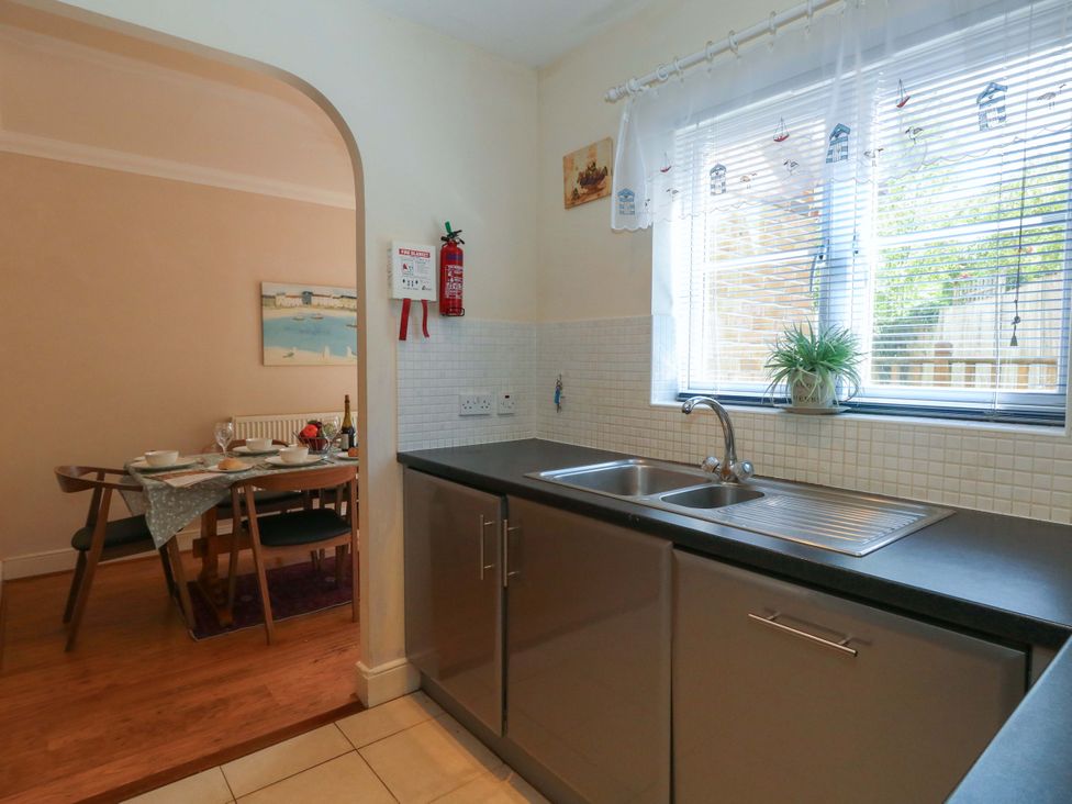 A kitchen with a sink and dining area at Farthings in Weymouth