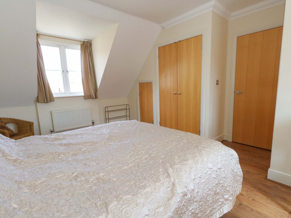 A bedroom with a bed, window, and wardrobe at Farthings in Weymouth