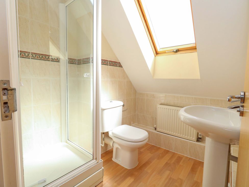 A bathroom with a shower, toilet, sink, and window at Farthings in Weymouth