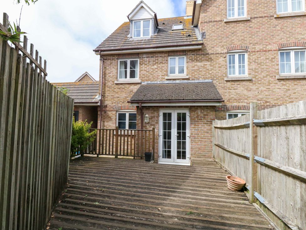 An outdoor area with a wooden deck and a house at Farthings in Weymouth