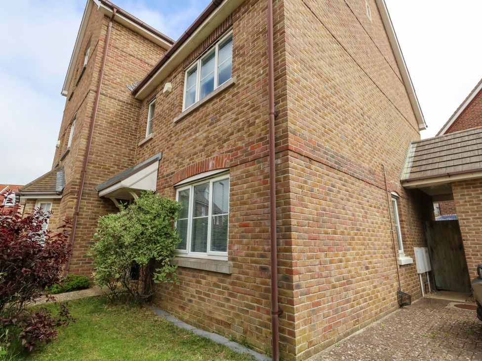 A brick exterior of a house with windows and greenery at Farthings in Weymouth