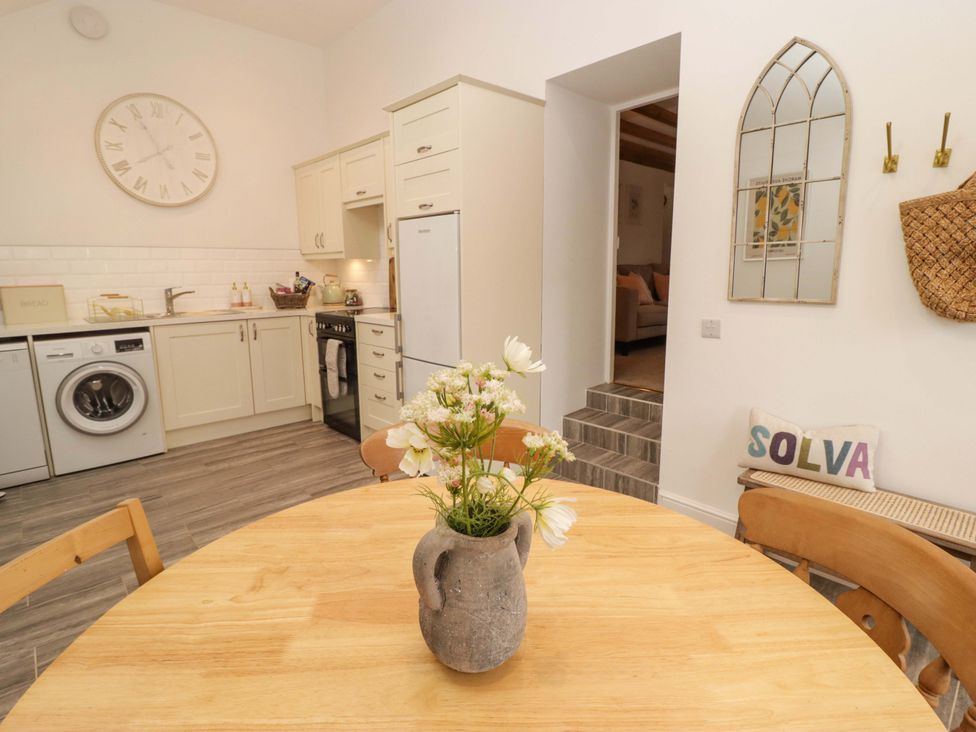 A kitchen with a dining table and washing machine at Penwyn Solva